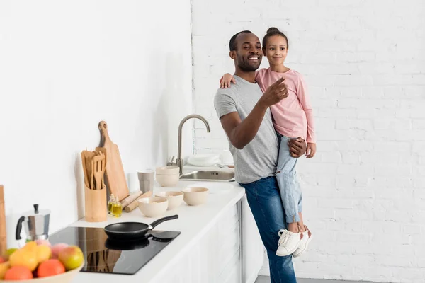 Schöner Vater Hält Seine Tochter Der Küche Und Zeigt Irgendwo — kostenloses Stockfoto