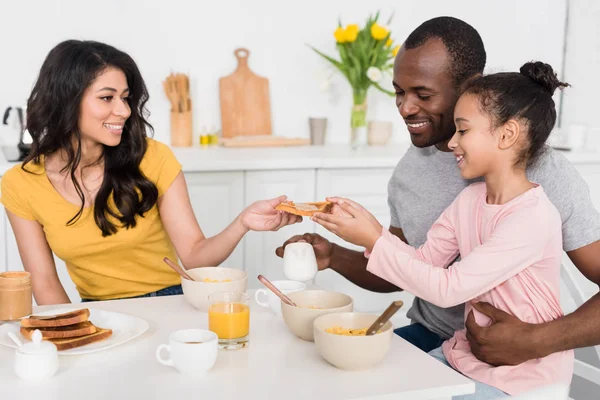 一緒にキッチンで健康的な朝食を持っている若い家族の笑顔 — ストック写真