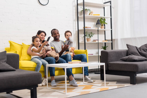 happy young family watching tv together at living room