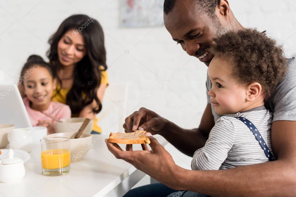 close-up shot of father applying peanut butter on toast for son at kitchen
