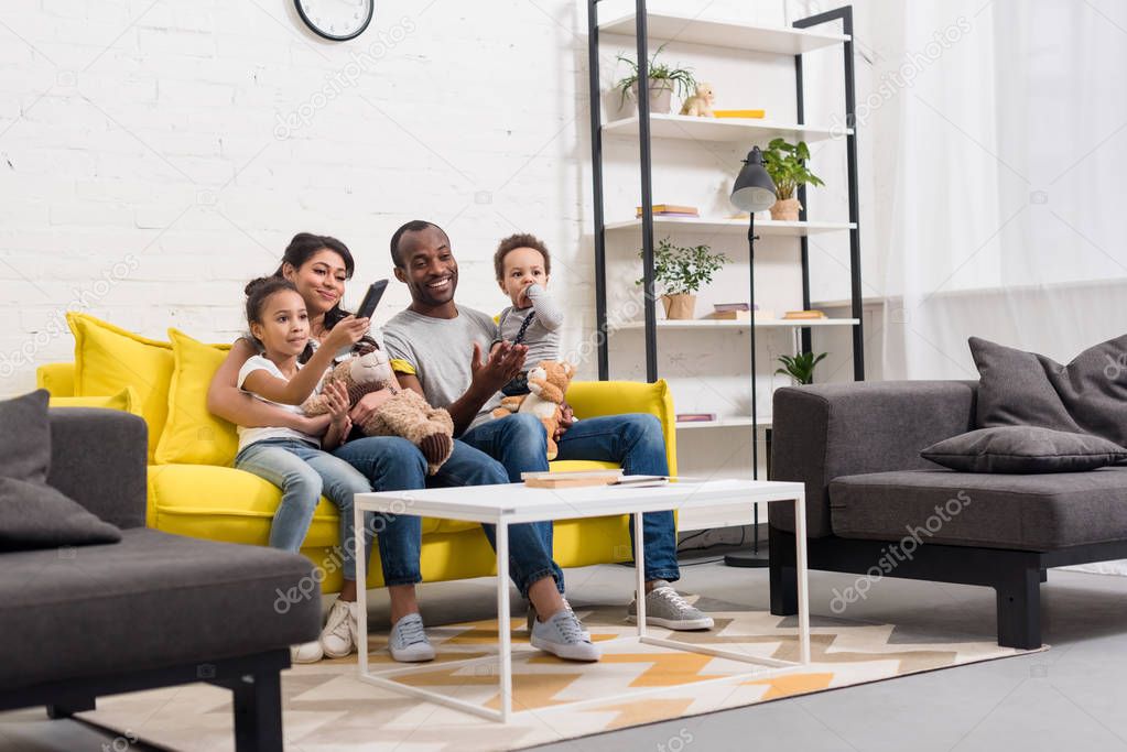 happy young family watching tv together at living room