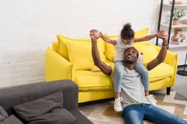 Baba ve kızı evde birlikte oynuyorlar.