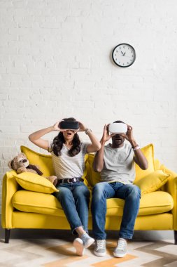 şok Afro-Amerikan çift kanepede oturan sanal gerçeklik kulaklık olarak