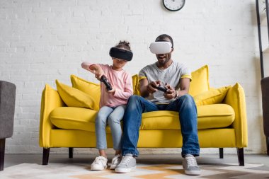 Baba ve kızı video oyunları oynarken vr kulaklıklar içinde evde kanepe