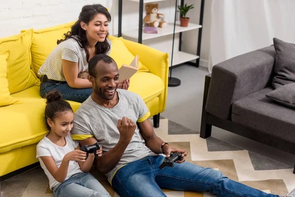 Padre Emocional Hija Jugando Videojuegos Mientras Madre Está Sentada Sofá — Foto de Stock