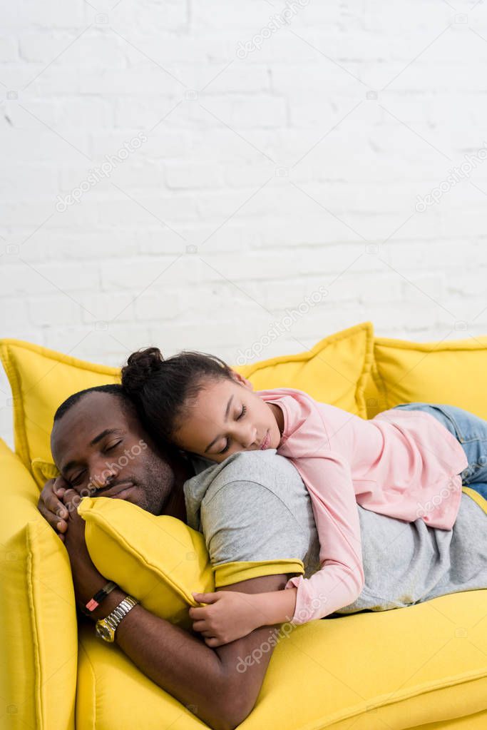 father and daughter sleeping together on couch
