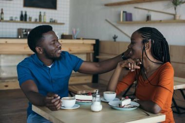 mutlu Afrika kökenli Amerikalı çift bardak kahve ve tatlılar kafede masada oturan