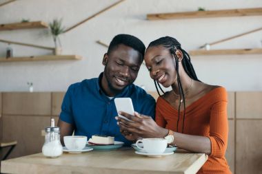Afrika kökenli Amerikalı çift Smartphone birlikte kahve dükkanında kullanma