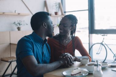 Elele ve birbirine kafede romantik tarihte bakarak bir Afrikalı-Amerikalı çift gülümseyen
