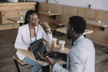 Afrika kökenli Amerikalı arkadaşları ile laptop kafede masada oturan