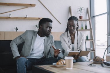 Cafe iş toplantısı sırasında tartışırken Afro-Amerikan iş adamları iş