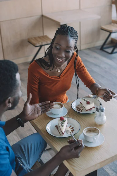 コーヒーとカフェでデザートのカップをテーブルに座っているアフリカ系アメリカ人のカップルの笑顔ハイアングル — ストック写真