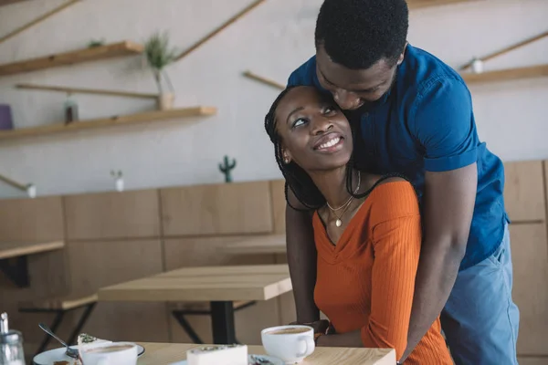 在咖啡店浪漫约会的非洲裔美国人男人拥抱女朋友 — 图库照片