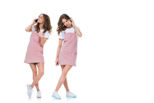 счастливые и злые близнецы разговаривают со смартфонами, изолированными на белом
