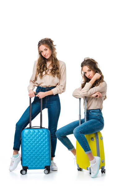 привлекательные молодые близнецы с сумками на колесах изолированы на белом, концепция путешествия
