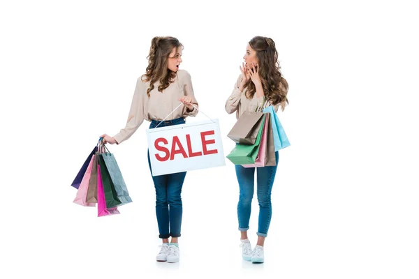 Überraschte Junge Zwillinge Mit Verkaufsschild Und Einkaufstüten Auf Weißem Grund — Stockfoto