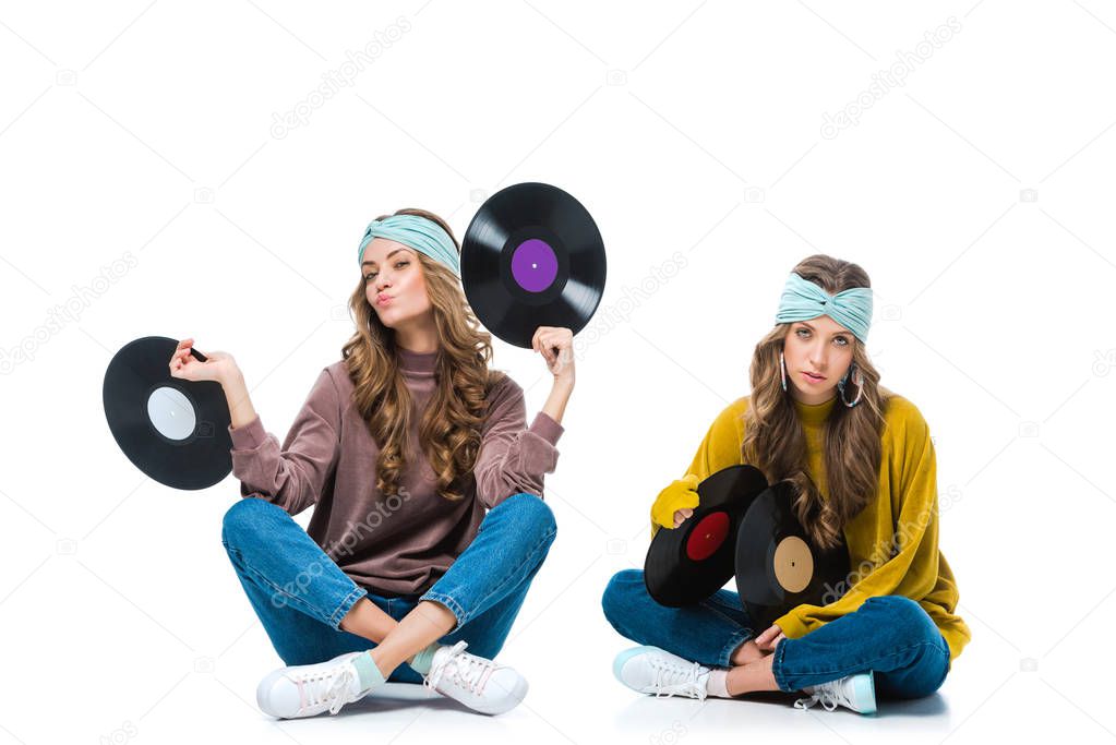 attractive retro styled young twins sitting with 12 inch vinyls isolated on white