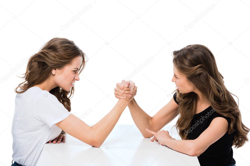 side view of angry twins armwrestling at table isolated on white