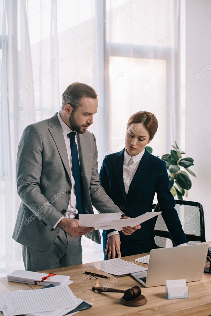 lawyers in suits working together on project at workplace with gavel and laptop in office