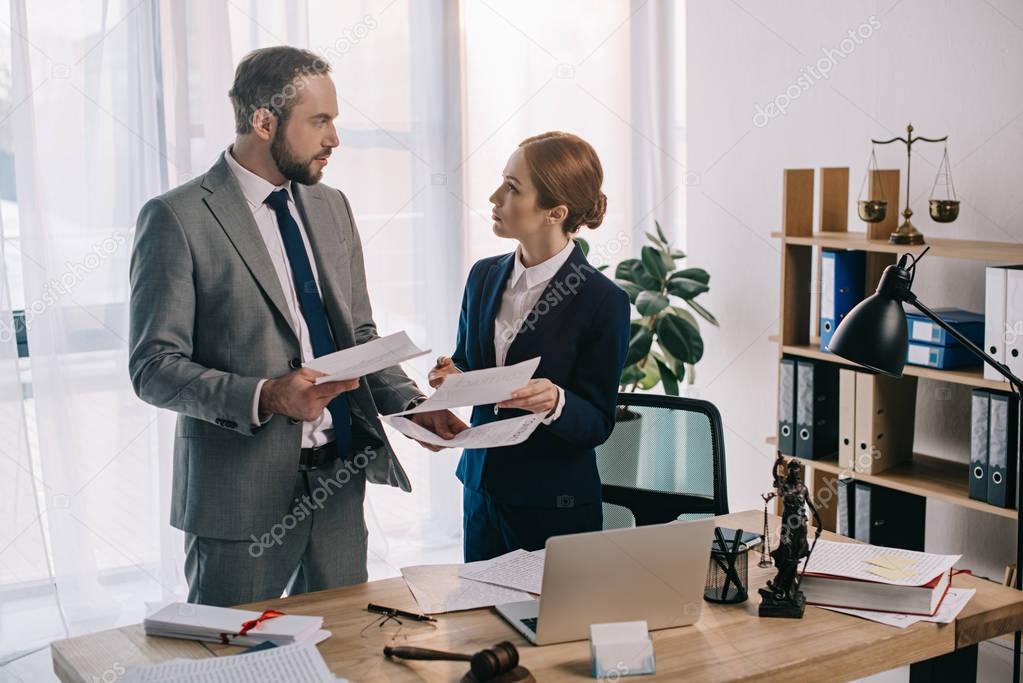 lawyers in suits working together on project at workplace with gavel and laptop in office