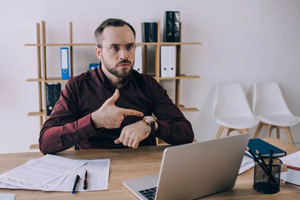 Porträtt Affärsmannen Pekar Klockan Handleden När Sitter Arbetsplatsen Med Laptop — Gratis stockfoto