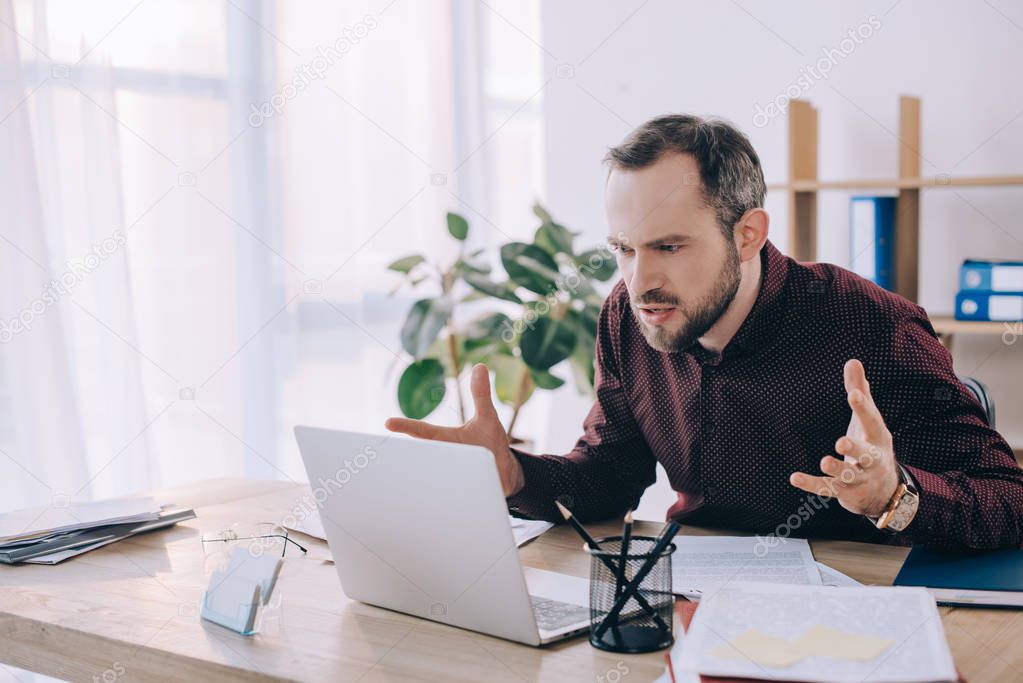 emotional businessman looking at laptop screen at workplace in office
