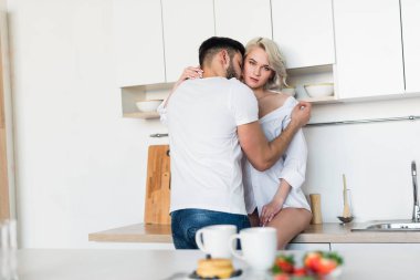 sarılma ve öpüşme seksi kız, kız kamera mutfakta genç adam