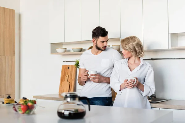Seductive Young Couple Holding Cups Coffee Looking Each Other Kitchen — Stock Photo, Image
