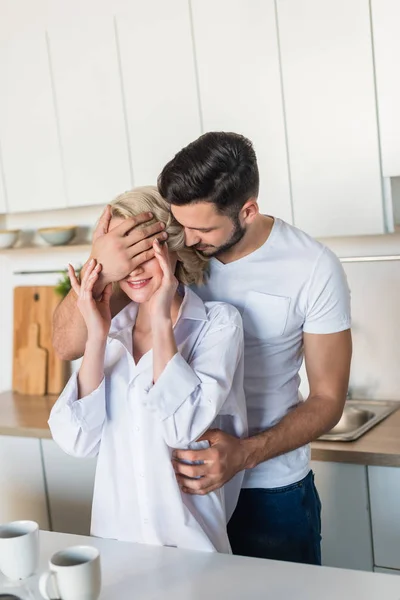 Stilig Ung Man Blundar Inför Leende Flickvän Köket — Stockfoto