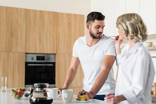 Young Woman Feeding Handsome Boyfriend Morning Kitchen — Free Stock Photo