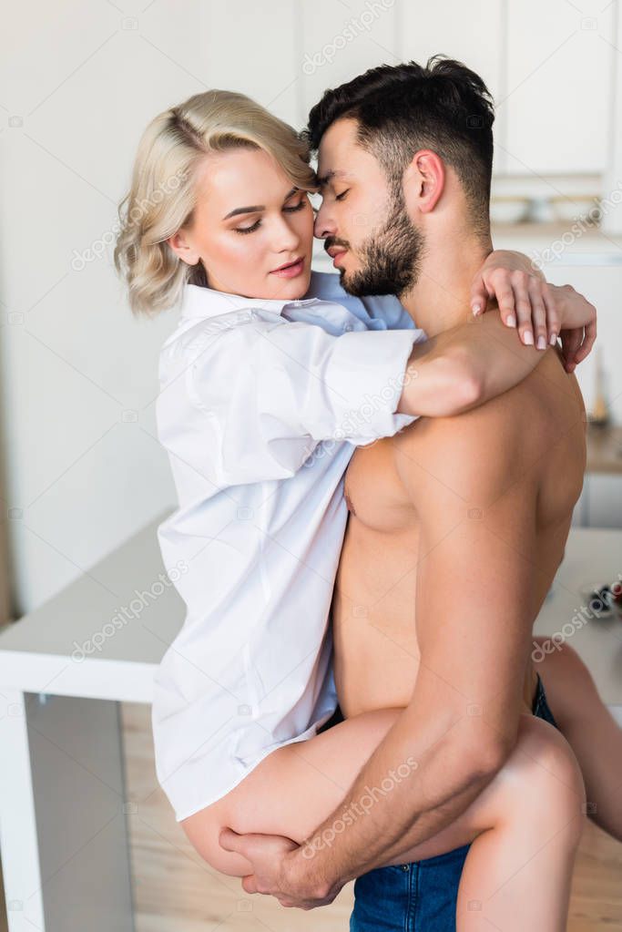 handsome shirtless young man hugging sexy girlfriend in kitchen 