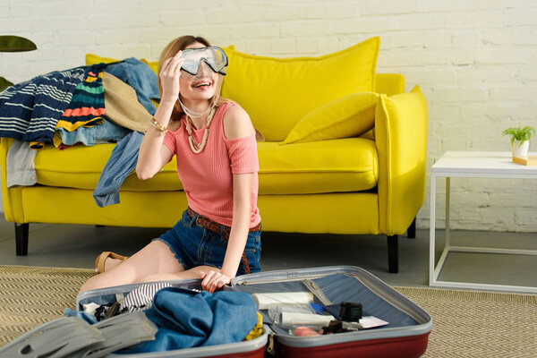 girl with snorkeling mask packing suitcase for travel