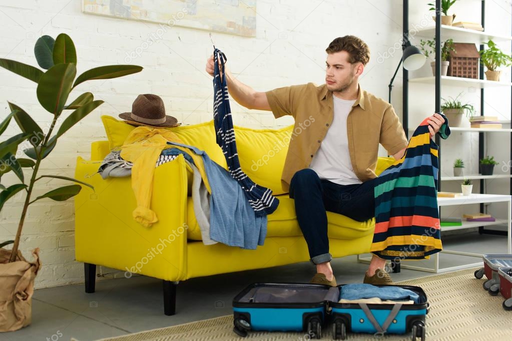 handsome man packing clothes into travel bag