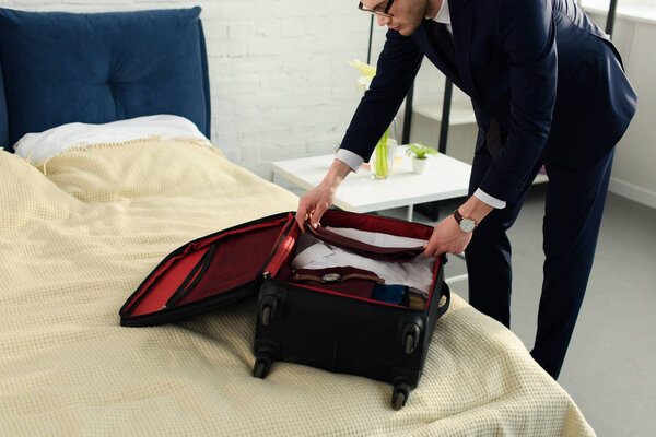 handsome professional businessman in suit packing baggage for business trip