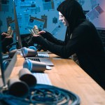 Visão lateral de hacker em máscara contando dinheiro roubado em seu local de trabalho