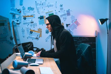 bilgisayarla çalışma kapüşonlu genç hacker yan görünüm
