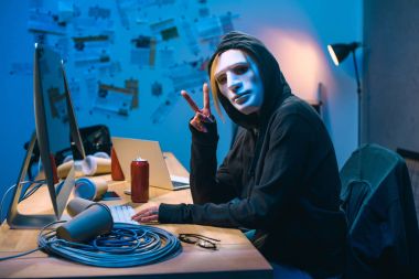 v işareti işyerinde gösterilen maskeli kadın hacker