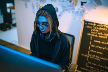 mavi ışık altında kötü amaçlı yazılım geliştirme kadın hacker yüksek açılı görünüş