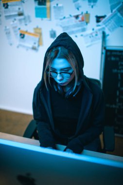 mavi ışık altında kötü amaçlı yazılım geliştirme genç kadın hacker yüksek açılı görünüş