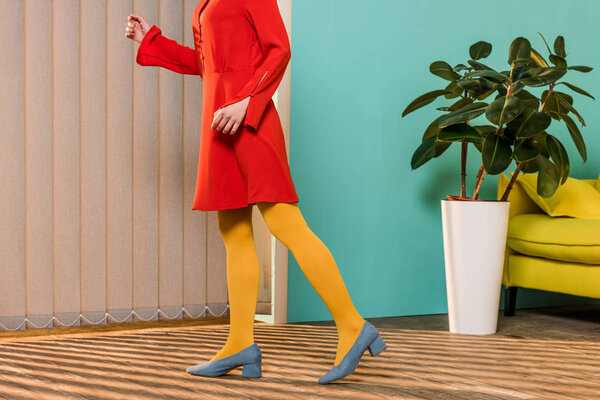 cropped shot of woman in bright clothing standing at colorful room, doll house concept