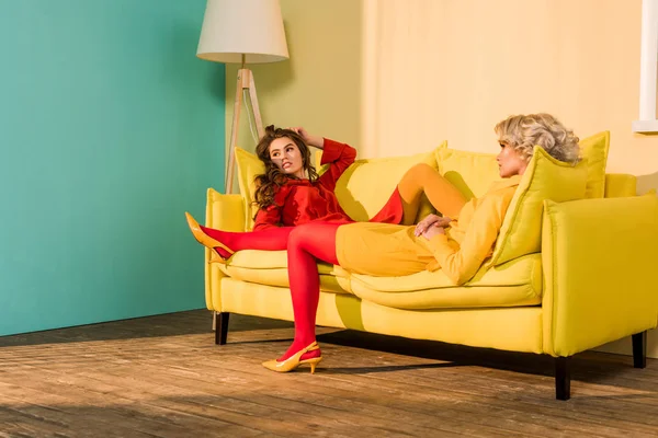 Retro Styled Beautiful Girls Colorful Dresses Lying Sofa Looking Away — Stock Photo, Image