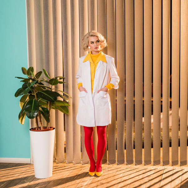 beautiful retro styled doctor standing in white coat and red tights in clinic