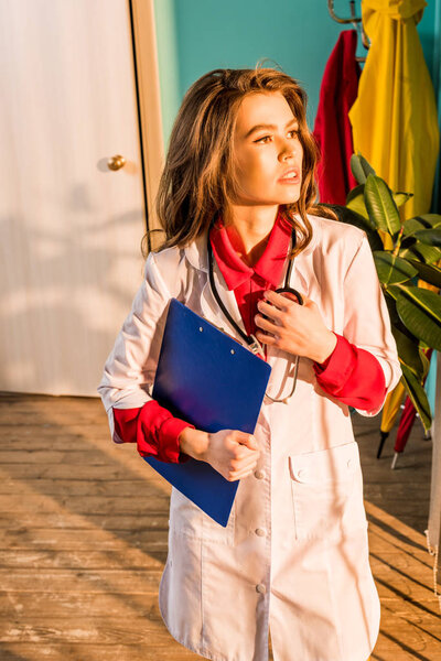 beautiful retro styled doctor with clipboard looking away in clinic