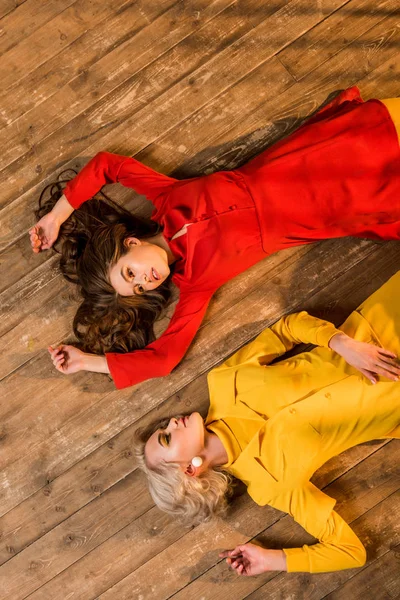 Top View Beautiful Retro Styled Girls Colorful Dresses Lying Floor — Free Stock Photo