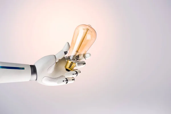 Robot Ręka Trzyma Żółta Lampka Beżowym Tle — Zdjęcie stockowe