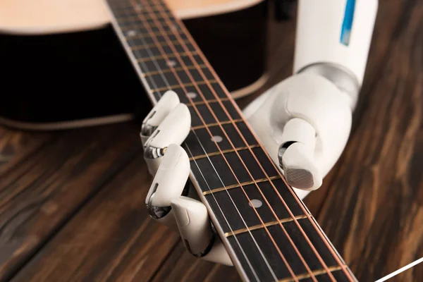 stock image cropped shot of robot playing guitar over wooden surface