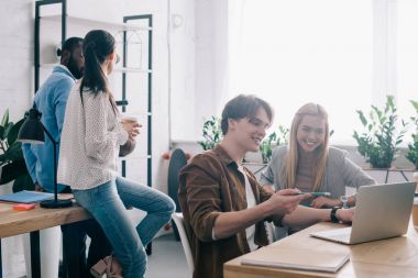 gülümseyen işadamı kadın partner ve meslektaşları ile kahve arkasında duran dizüstü bilgisayar ekranında kalem tarafından işaret 