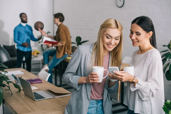 Smiling Businesswomen Smartphone Coffee Mugs Businessmen Standing Ball — Stock Photo, Image