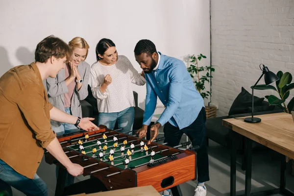 Hombres Negocios Multiétnicos Jugando Futbolín Colegas Mujeres Animándolos — Foto de Stock