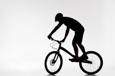 Beyaz Bisiklet üzerinde Dengeleme kask içinde deneme motorcu silüeti